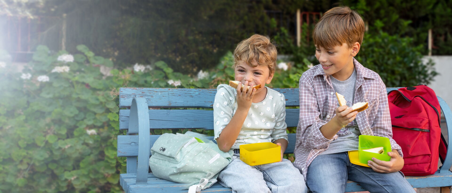Frühstückpause - zwei Kinder auf Bank essen Pausenbrot